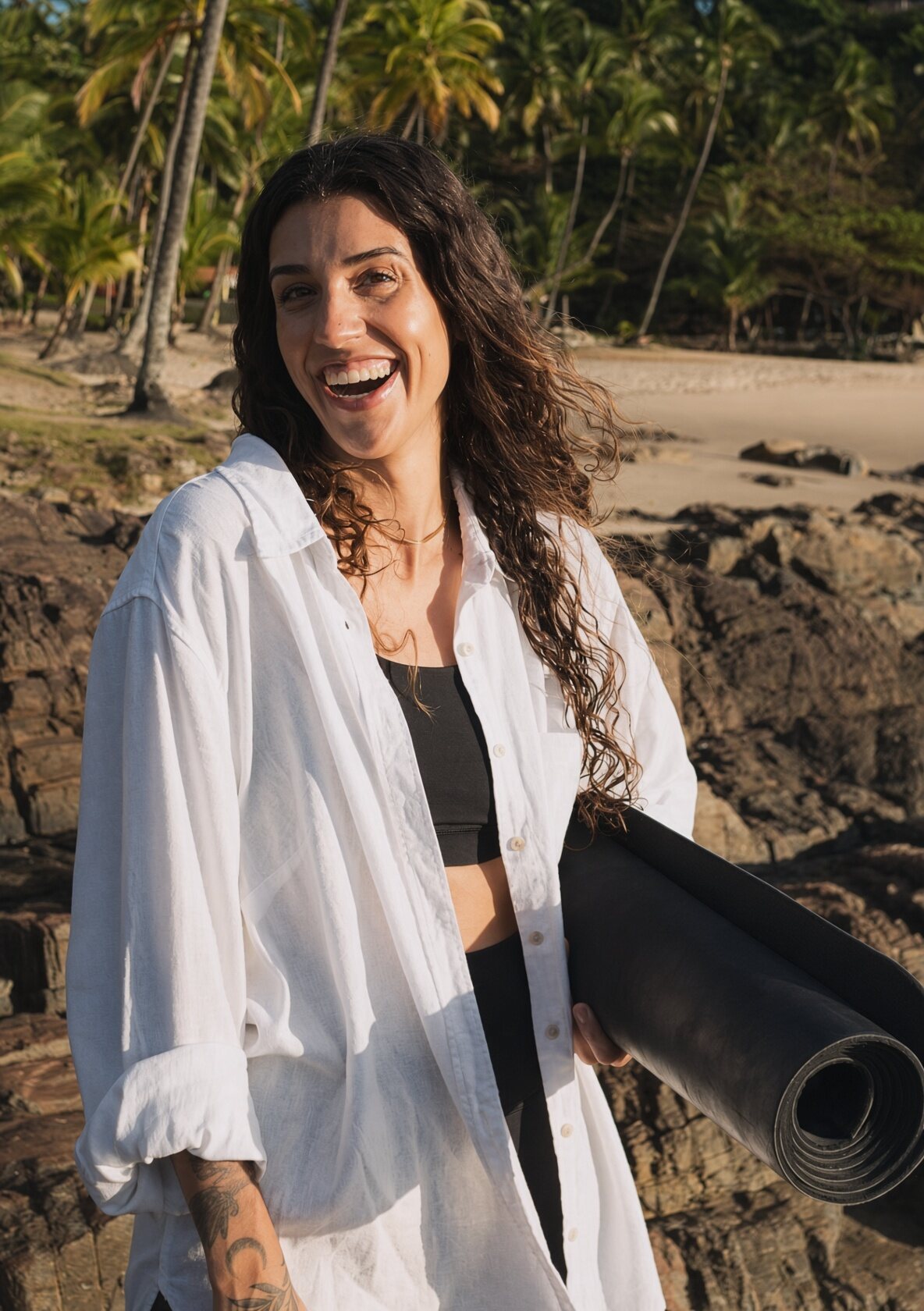 Mayra rindo com o tapete debaixo do braço, Praia da Concha ao fundo